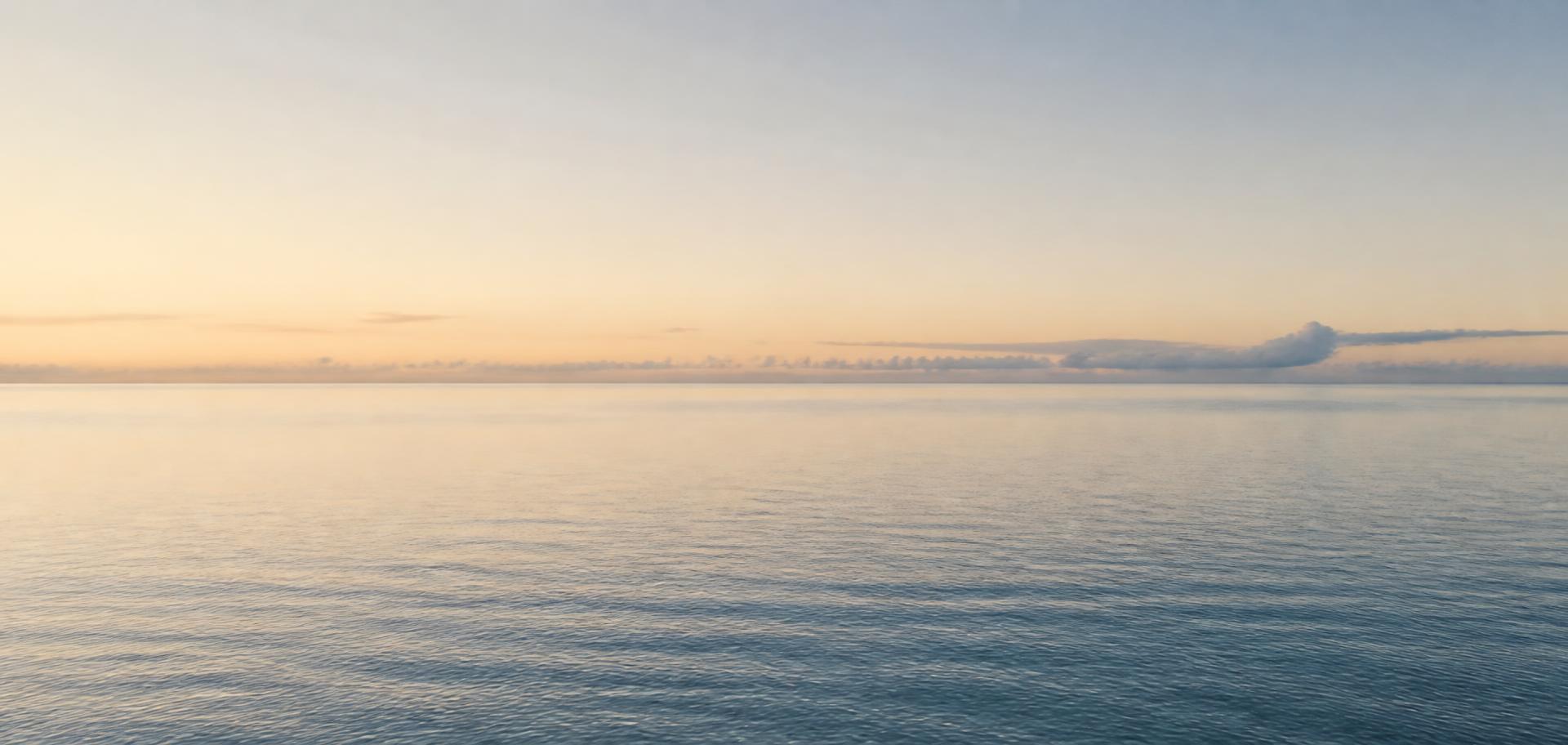 Calm open water meeting the horizon at dawn